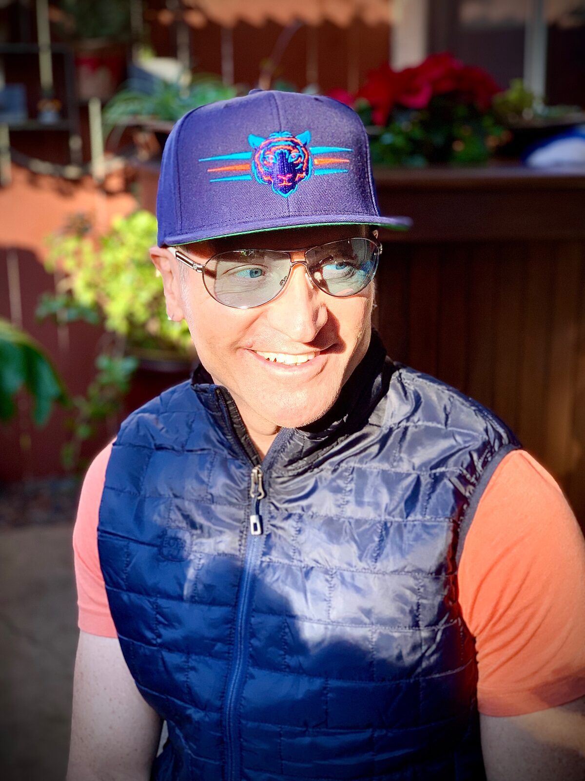 Lance smiling in the sun, wearing a ball cap and vest