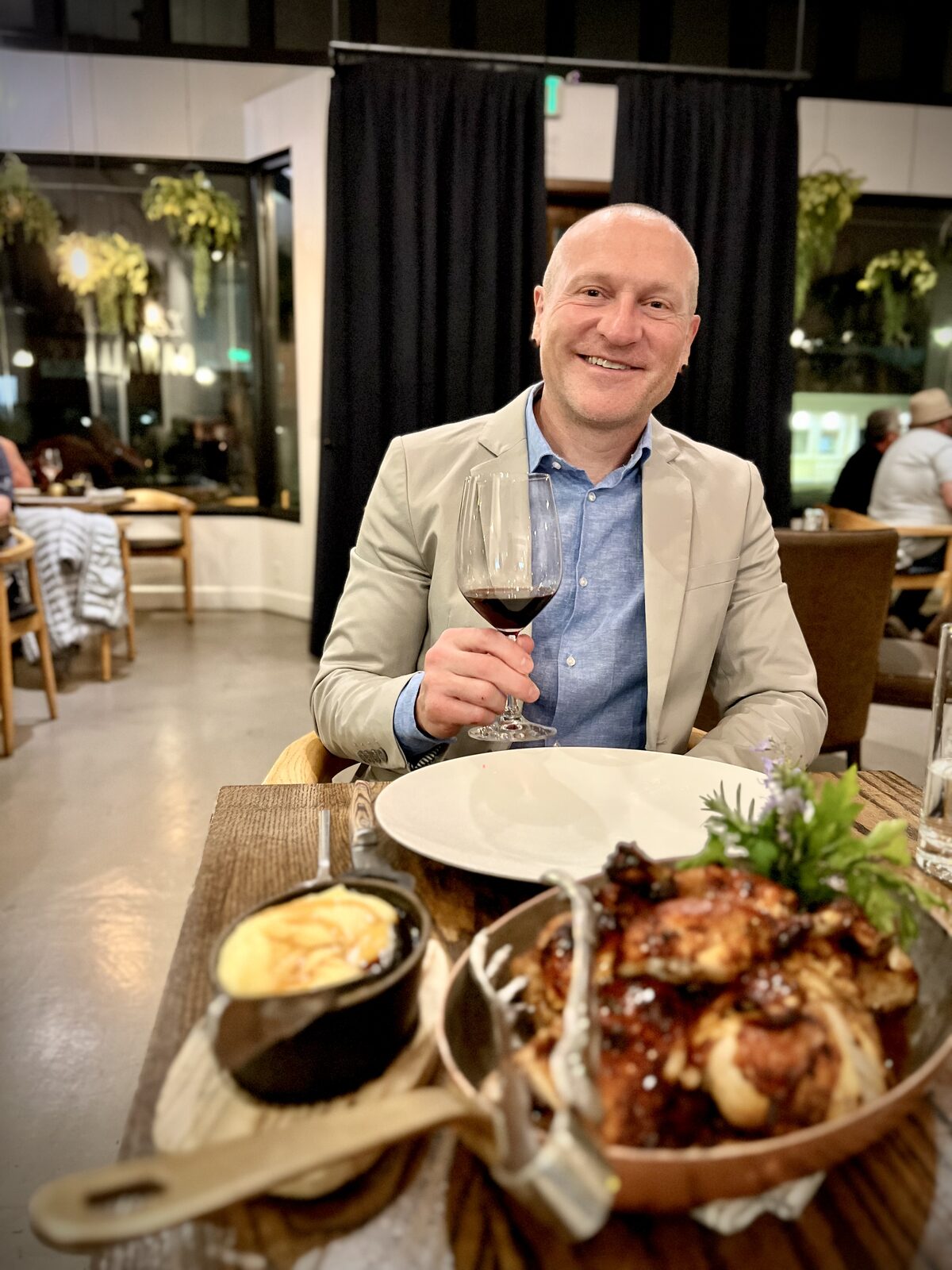 Lance LaSpina smiling at a restaurant table with a glass of red wine